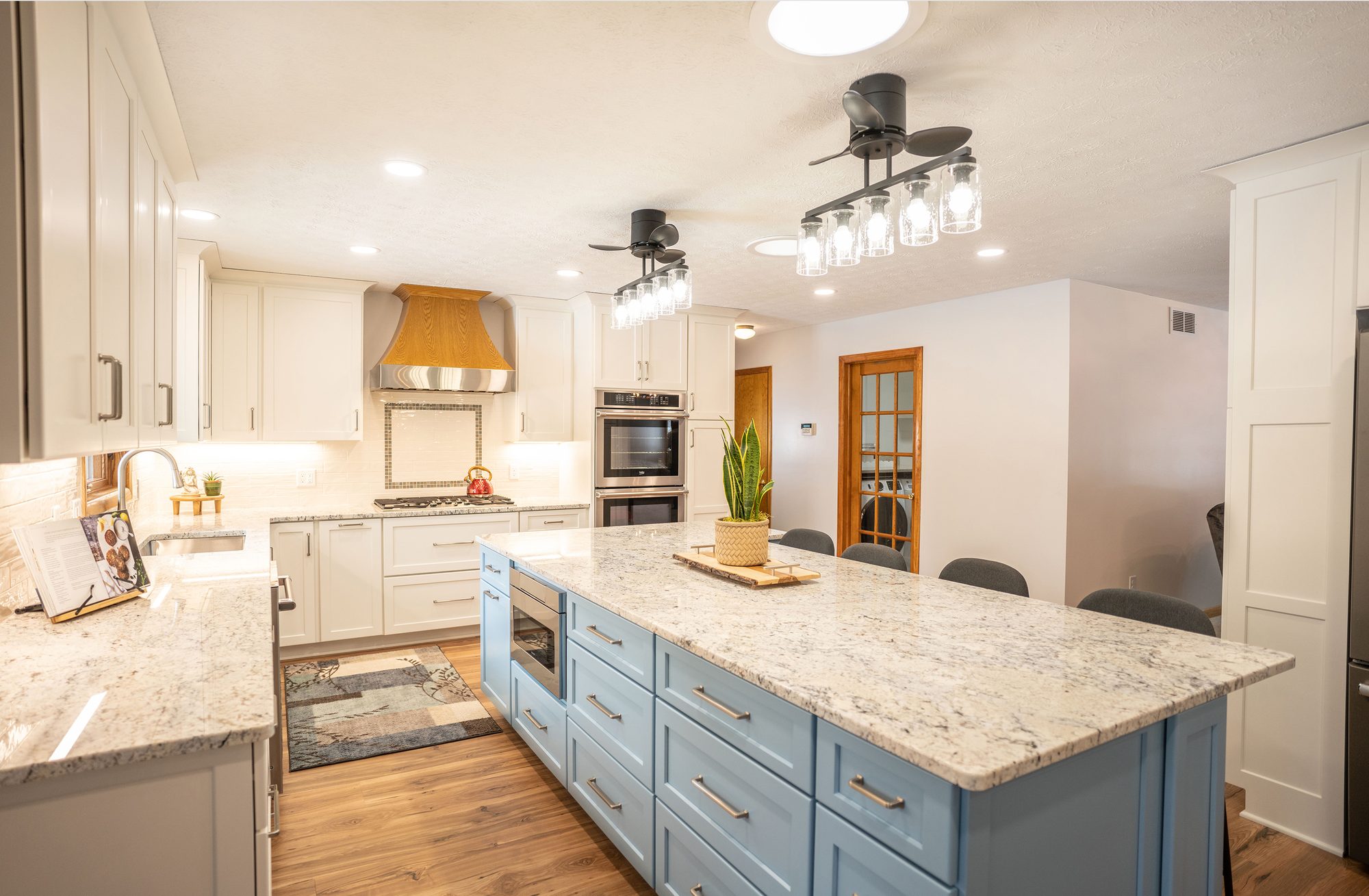 Remodeled kitchen with a navy-blue island, white cabinetry and granite countertops
