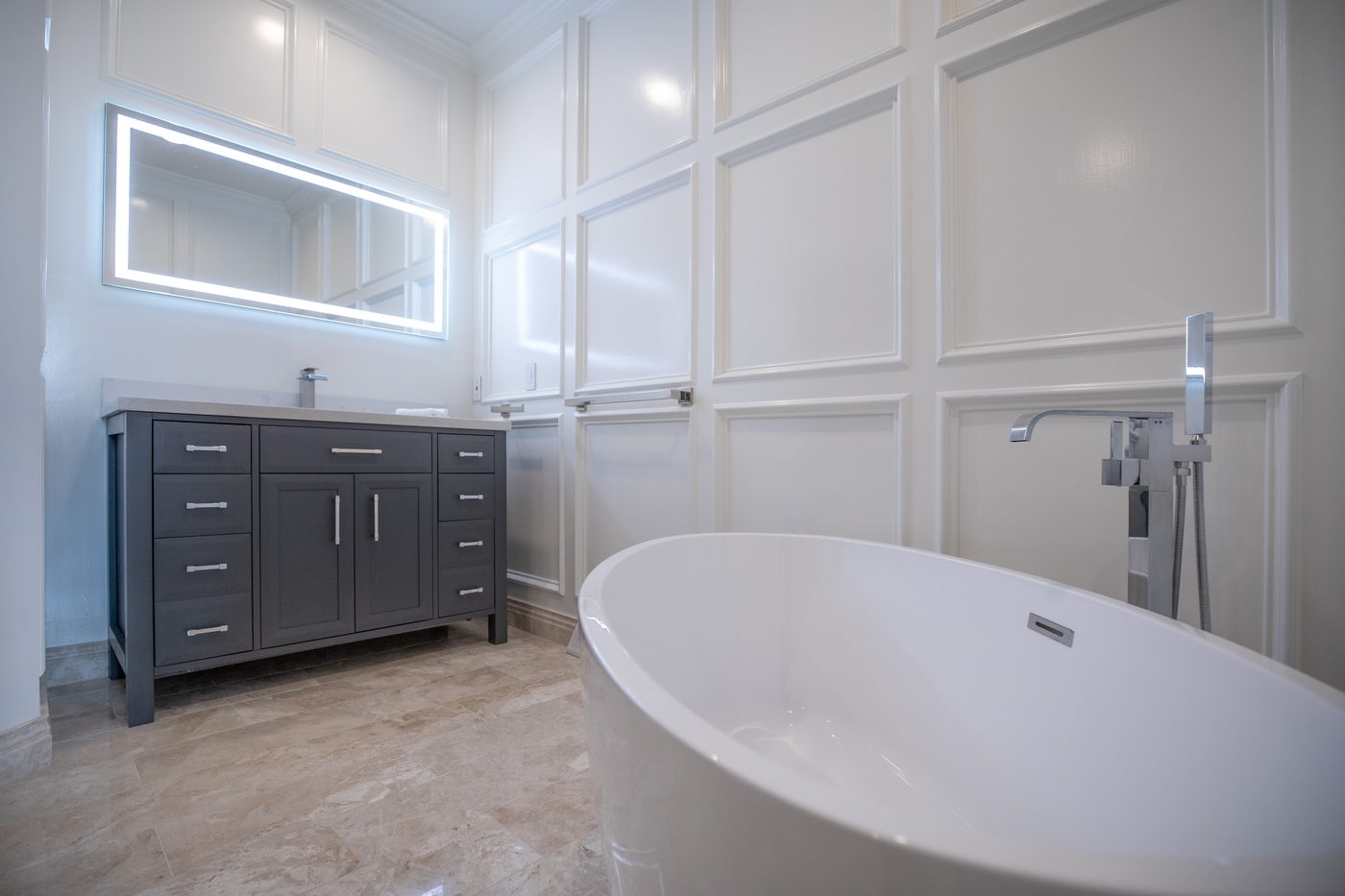 Remodeled bathroom with a freestanding soaking tub and marble tile surround
