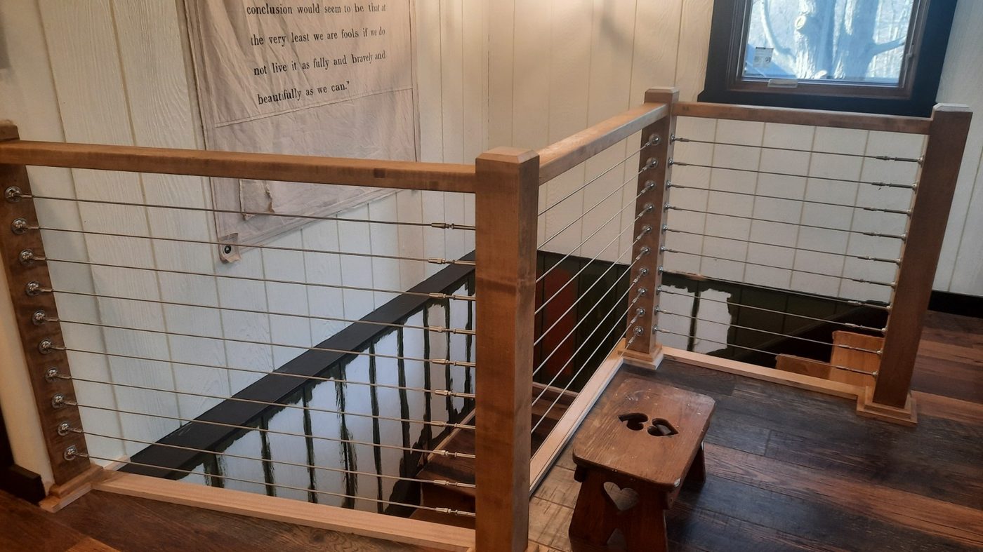 Custom wood-and-cable stair railing built by David Brown Construction