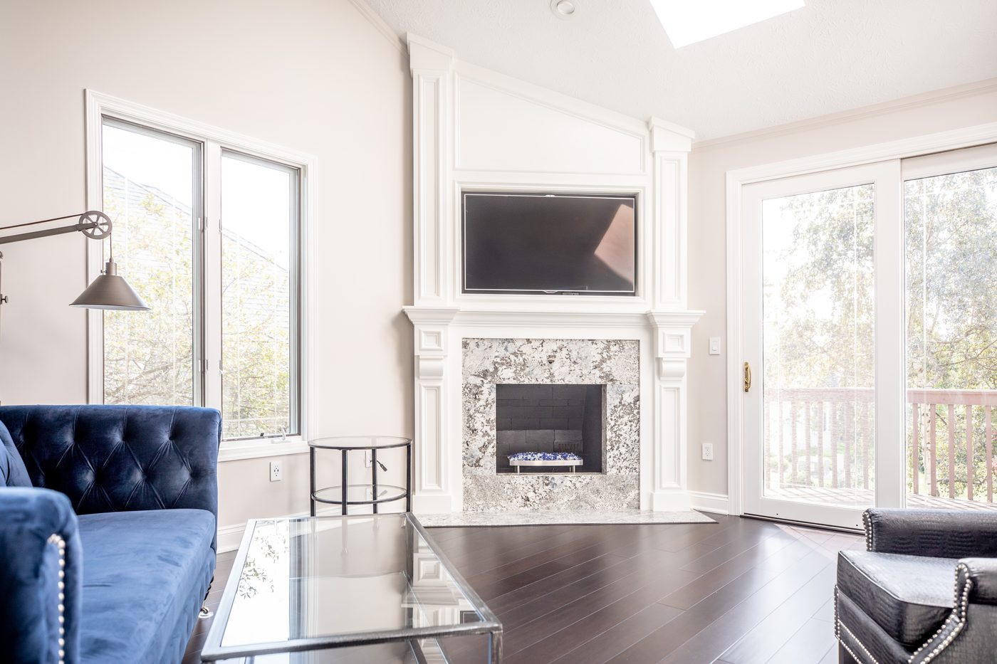 Remodeled living room with a tufted blue chair and dark wood flooring