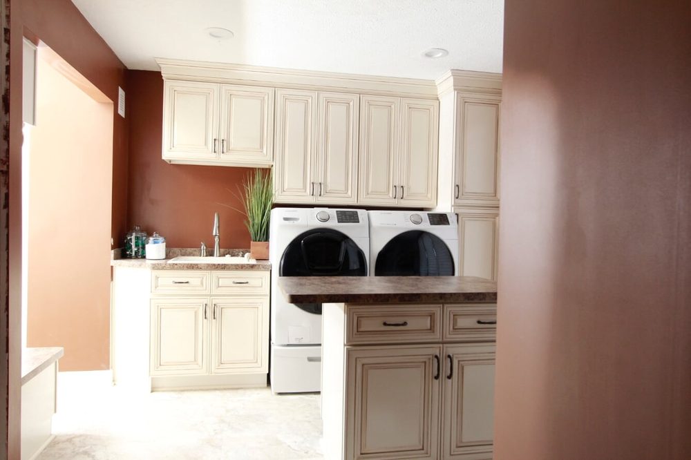 Remodeled laundry room with dark accent walls and white cabinetry