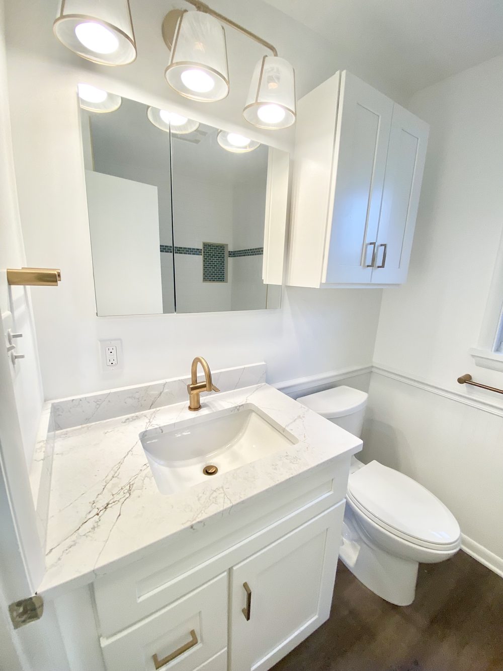 Bathroom vanity remodel with marble countertop and gold fixtures